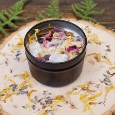 a black bowl filled with ice and flowers on top of a wooden table next to green plants