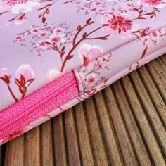 a close up of a pink flowered case on a wooden table with wood slats