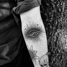 a person with a tattoo on their arm next to a tree and a sunflower