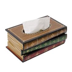 three books stacked on top of each other with a tissue paper dispenser