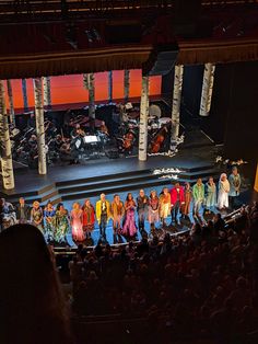 a group of people standing on top of a stage next to each other in front of an audience