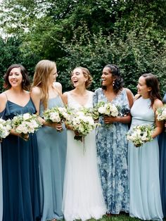 a group of women standing next to each other holding bouquets in their hands and laughing