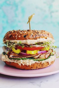 a sandwich on a pink plate with a toothpick sticking out of the top