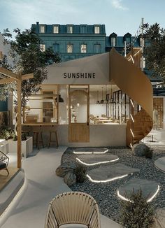 an outdoor store with steps leading up to the front door and outside seating area, surrounded by greenery