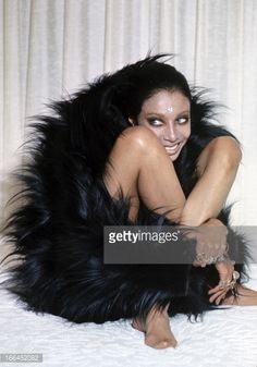 a woman is laying on the bed with her legs spread out and wearing black fur