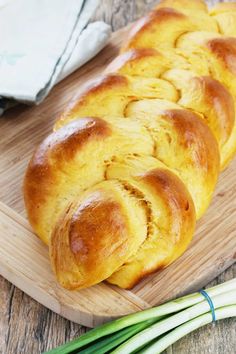 some bread on a wooden cutting board next to green onions