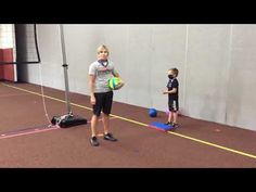 two children are playing with a ball in an indoor gym area while another child watches from the sidelines