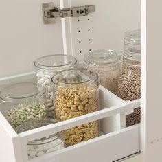 an organized pantry drawer with jars and food items in the bins on the bottom shelf