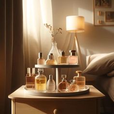 an assortment of perfumes on a table next to a bed