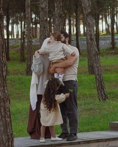 a man and woman holding a child in their arms while standing on a wooden platform