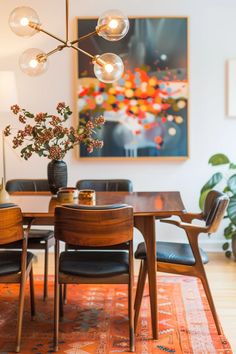 a dining room table with four chairs and a large painting on the wall