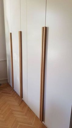 three tall wooden poles are in the corner of a room with white walls and wood flooring