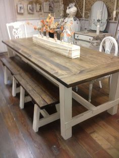 a wooden table sitting on top of a hard wood floor next to two white chairs