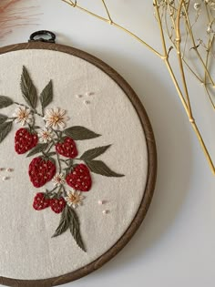 a close up of a embroidery on a white surface with flowers and leaves around it