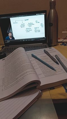 an open book sitting on top of a table next to a laptop computer