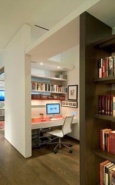 a home office with bookshelves, desk and computer on top of the shelves