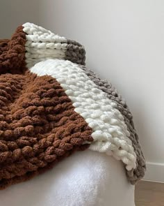 a white mannequin head wearing a brown and white crocheted blanket on top of it