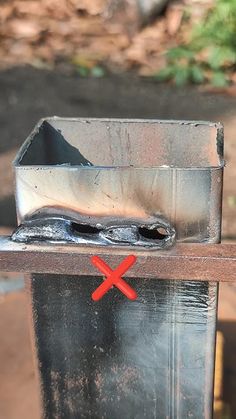 a piece of metal sitting on top of a wooden table next to a trash can