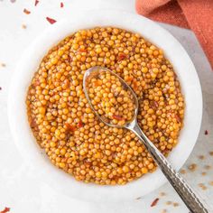 a white bowl filled with cooked chickpeas on top of a table next to a spoon