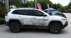 a dirty white jeep parked in a parking lot