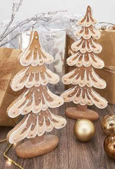 two wooden christmas trees next to presents on a table