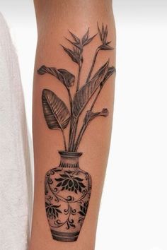 a black and white photo of a vase with plants in it on the leg tattoo