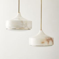 two white marble lamps hanging from gold colored wires and one is turned off to the side