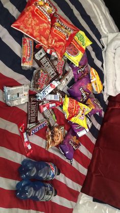 a pile of candy on top of a red and white striped bed spread next to an american flag