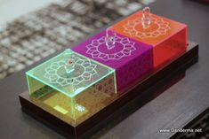 three colorful boxes with candles in them sitting on a table