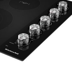 four knobs on the side of a black stove top with five different burners