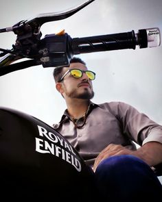 a man wearing sunglasses sitting on the back of a motorcycle with his bike attached to it's handlebars