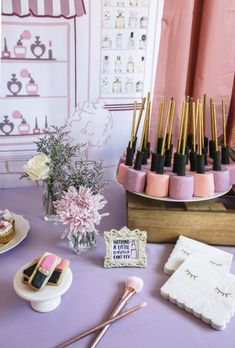 a table topped with cakes and desserts on top of a purple cloth covered table