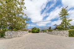 an empty driveway surrounded by stone walls and trees