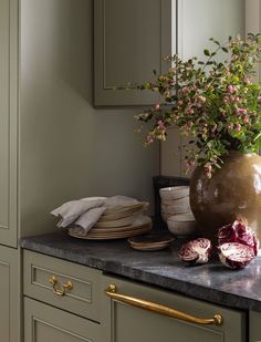 a vase filled with flowers sitting on top of a counter next to plates and bowls