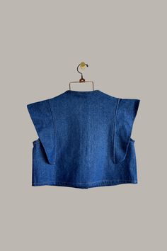 a denim top hanging on a hanger with a bird perched on the back of it