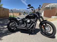 a black motorcycle parked on the street in front of a house with mountains in the background