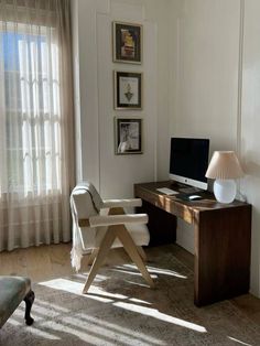 a desk with a computer on top of it in front of a curtained window