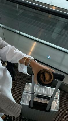 a woman sitting on top of a metal chair next to a luggage bag in an airport