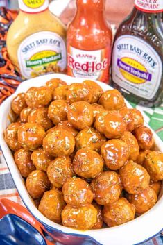 a white bowl filled with meatballs next to bottles of ketchup and mustard