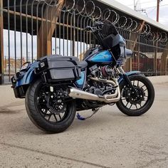 a blue motorcycle parked in front of a fence