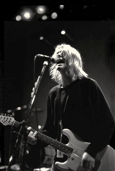 black and white photograph of man playing guitar on stage