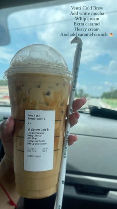 a person holding up a plastic cup filled with ice cream and chocolate chip flavored drink