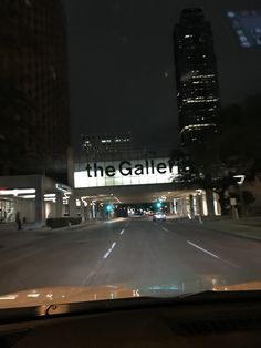 the interior of a car driving down a city street at night with skyscrapers in the background