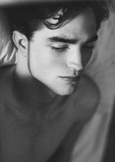 black and white photograph of a man laying in bed with his eyes closed looking off to the side