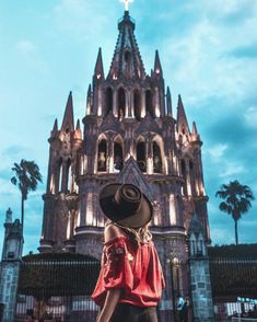 a woman wearing a hat standing in front of a church