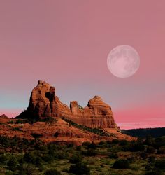 the full moon is setting over red rock formations