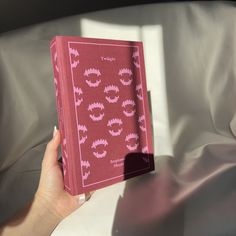 a person is holding up a pink book with red lipstick on it and white sheets