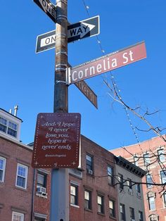 the street signs are clearly visible for everyone to see on this pole in front of some buildings