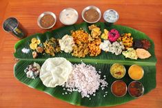 a banana leaf filled with different types of food and condiments on top of it