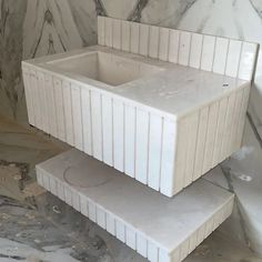 two white boxes stacked on top of each other in front of a marble wall and floor